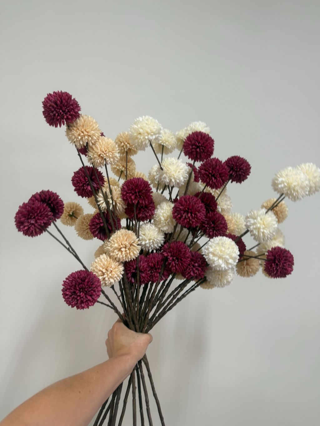 Kunsttaken met pompomachtige bloemen in wit, crème en bordeaux kleur.