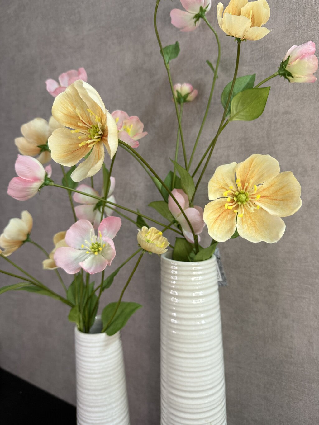 Vensterbank set Mell met twee witte vazen en bloemen in crème, roze en geel.