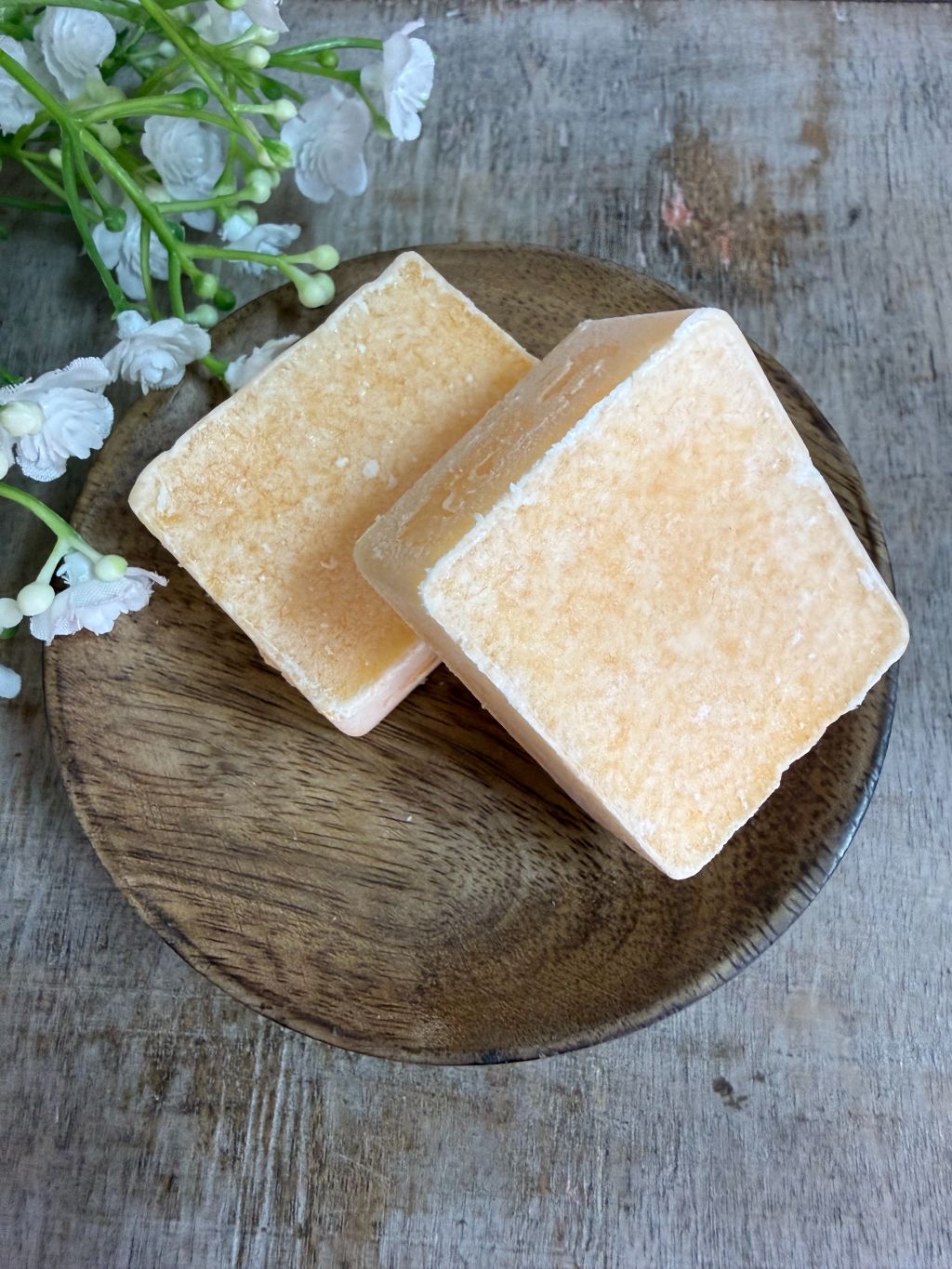 Beige amberblokjes met leliegeur op een houten schaaltje.