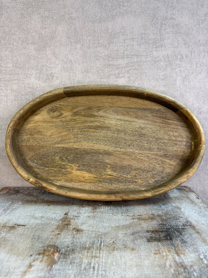 Ovaal houten dienblad met opstaande rand op een houten ondergrond.