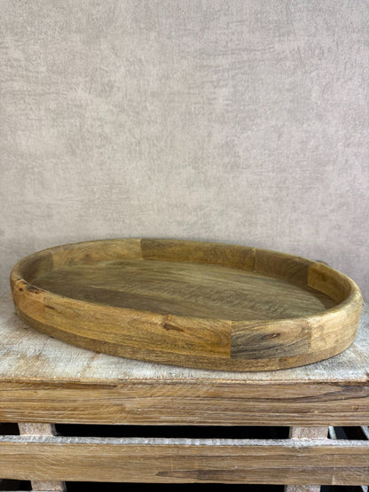 Ovaal houten dienblad met opstaande rand op een houten ondergrond.