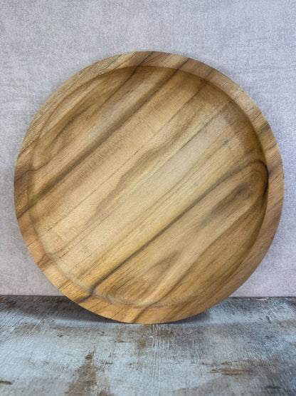 Dienblad Teak – rond houten dienblad van teakhout met natuurlijke nerven op een rustieke ondergrond.
