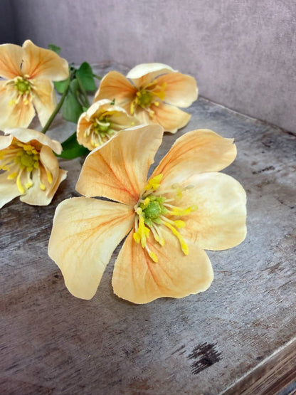 Kunstbloem Melastoma met zachte gele bloemen en groene bladeren tegen een neutrale achtergrond.