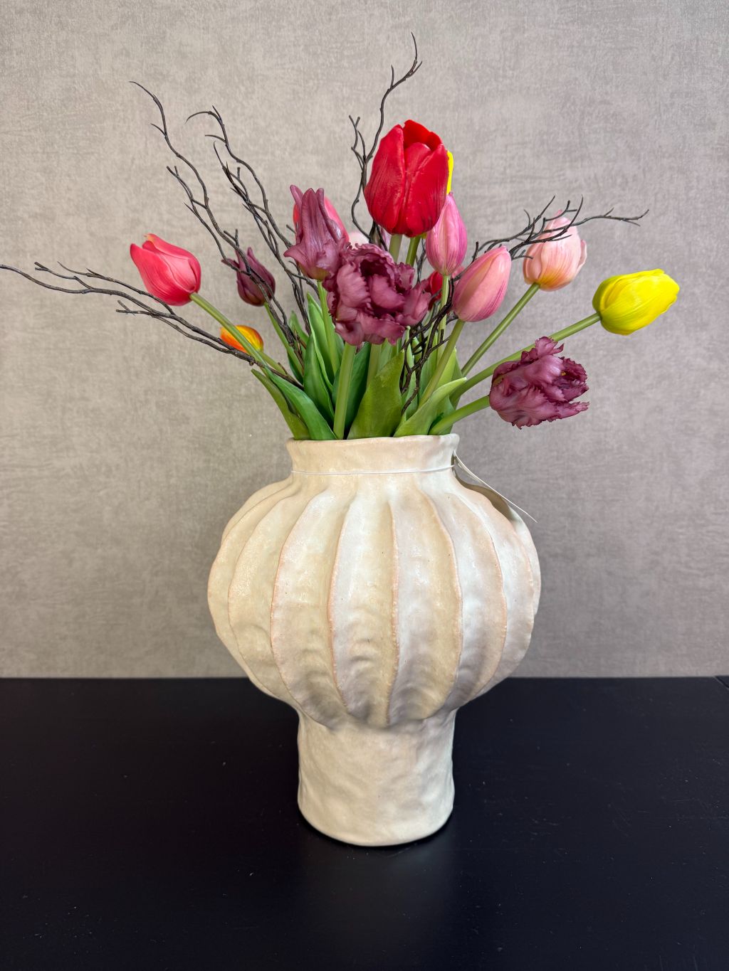 Kleurrijk kunstboeket met tulpen en decoratieve takken in een lichte vaas, vrolijke uitstraling en realistische afwerking.