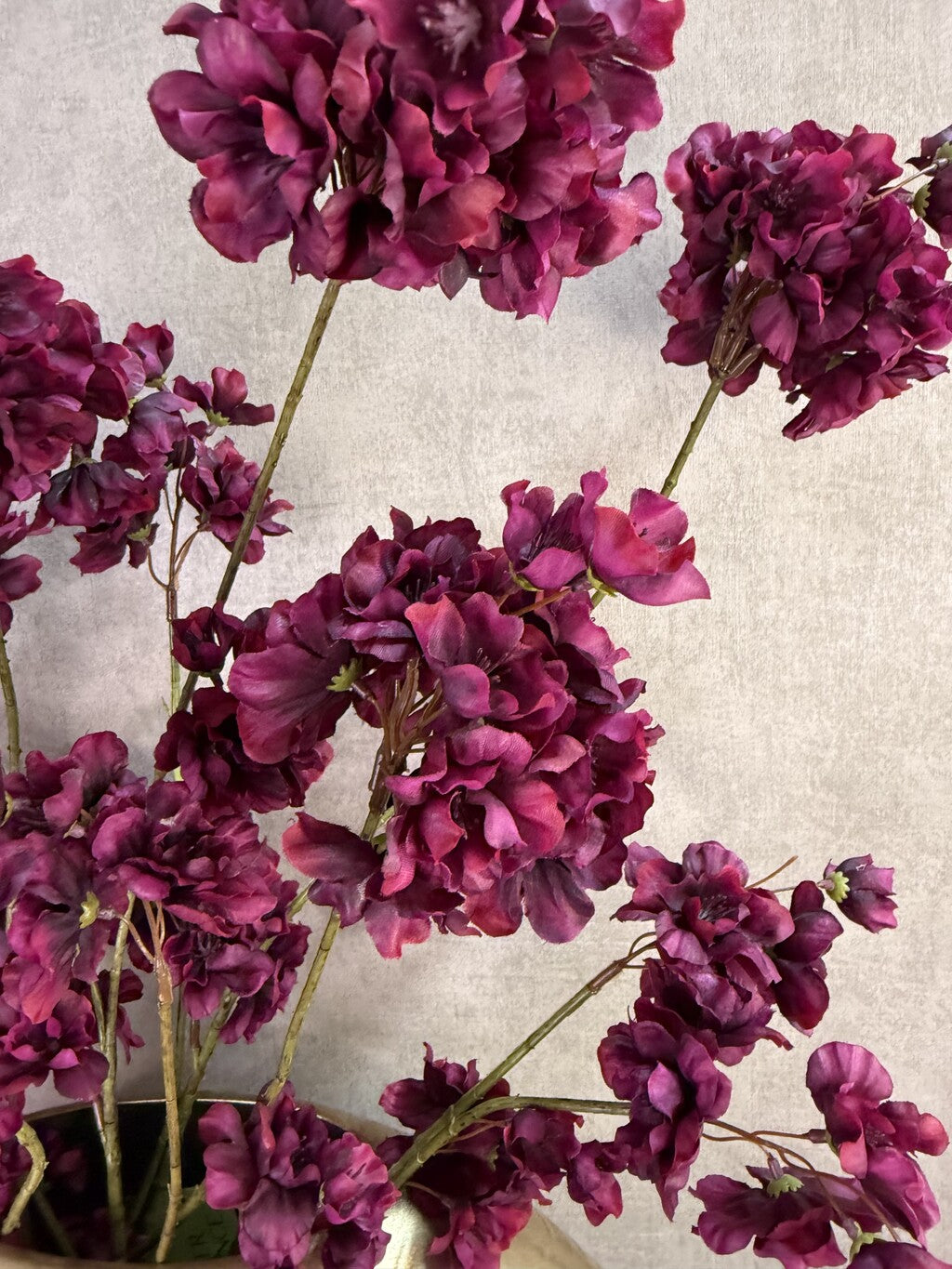 Kunstboeket Prunus in aubergine kleur in een grote ronde vaas met reliëf.