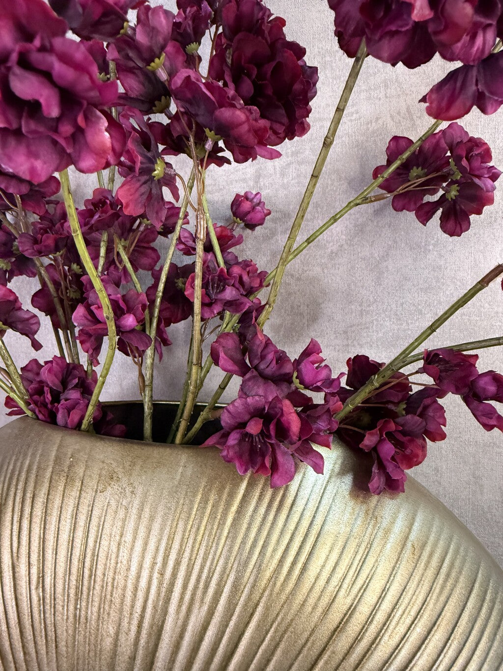 Kunstboeket Prunus in aubergine kleur in een grote ronde vaas met reliëf.