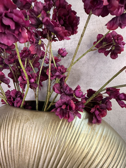 Kunstboeket Prunus in aubergine kleur in een grote ronde vaas met reliëf.