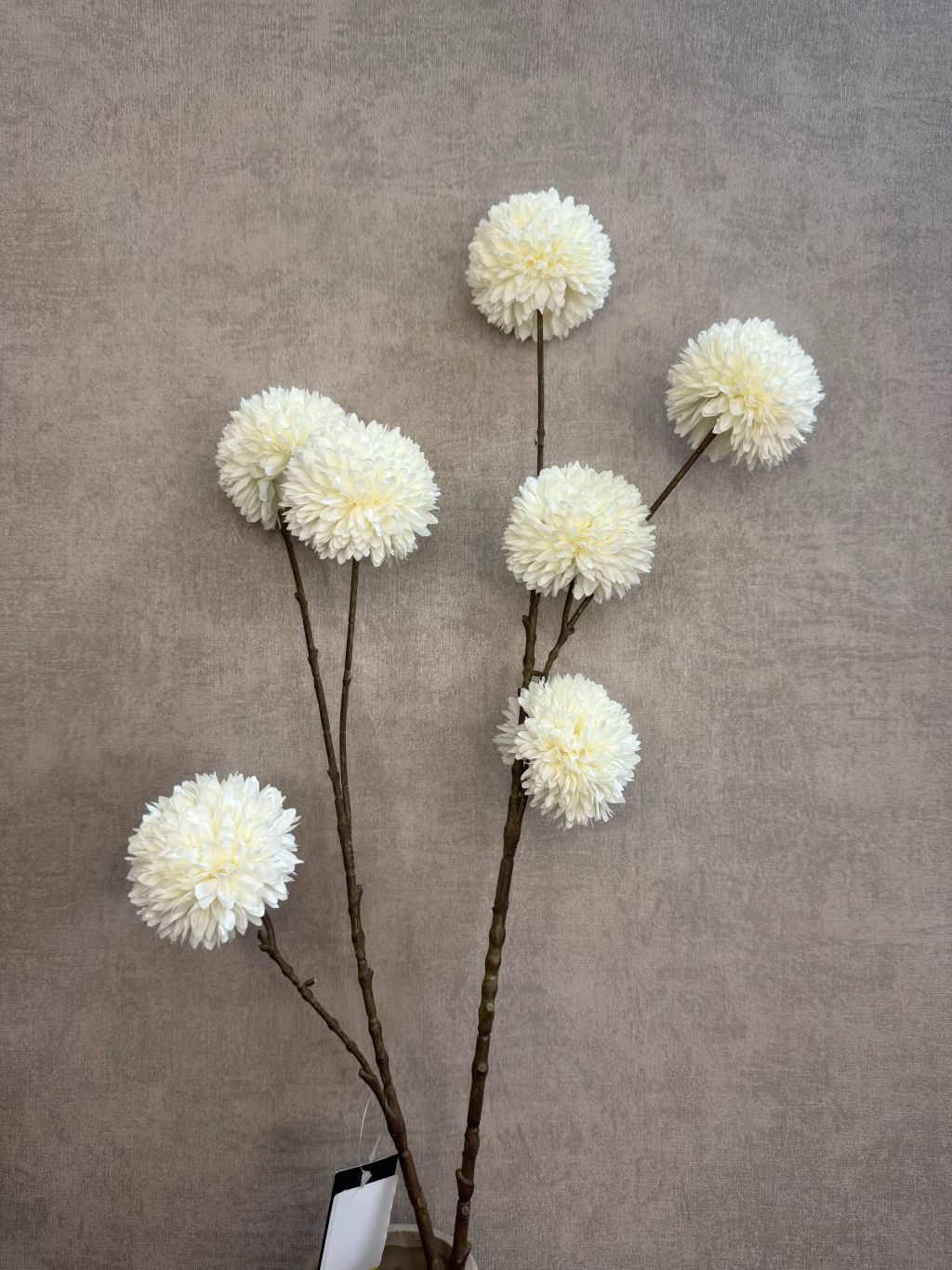 Witte kunsttak met pompomachtige bloemen op donkere steel, geschikt voor frisse, lichte interieurs.