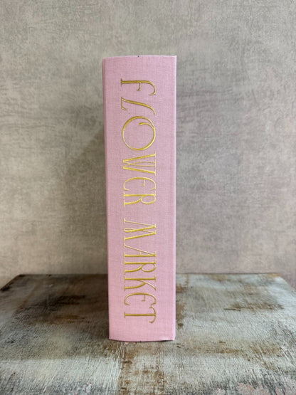 Roze opbergboek Flower Market met bloemenillustratie en gouden tekst, staand op een houten ondergrond.