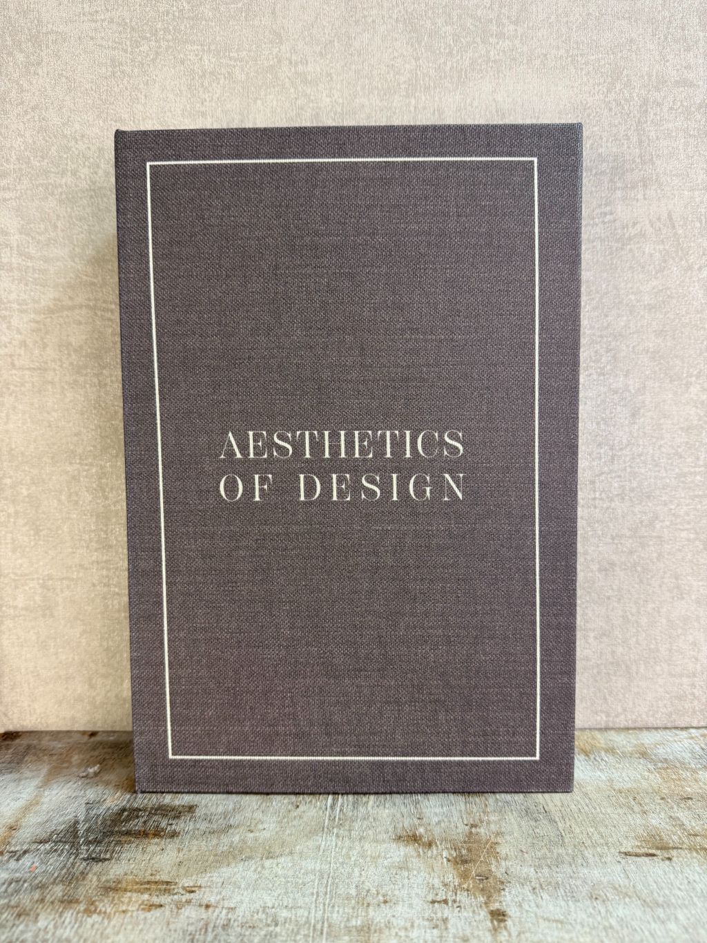 Bruin opbergboek Aesthetics of Design met witte omlijning en tekst, staand op een houten ondergrond.