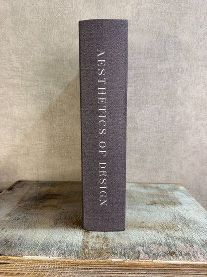 Bruin opbergboek Aesthetics of Design met witte omlijning en tekst, staand op een houten ondergrond.