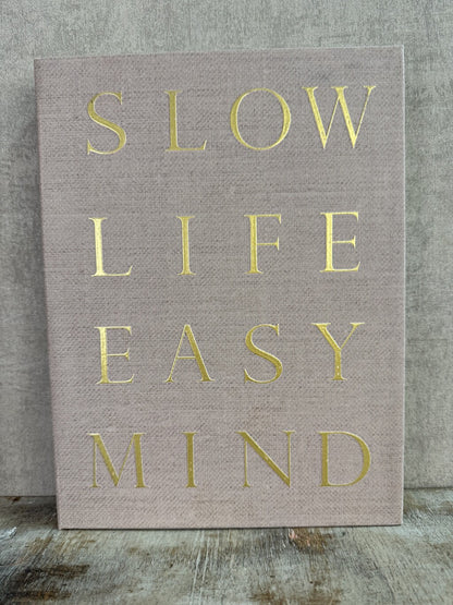 Beige opbergboek van Homebound met goudkleurige tekst Slow Life Easy Mind en een bruin opbergvak aan de binnenzijde.