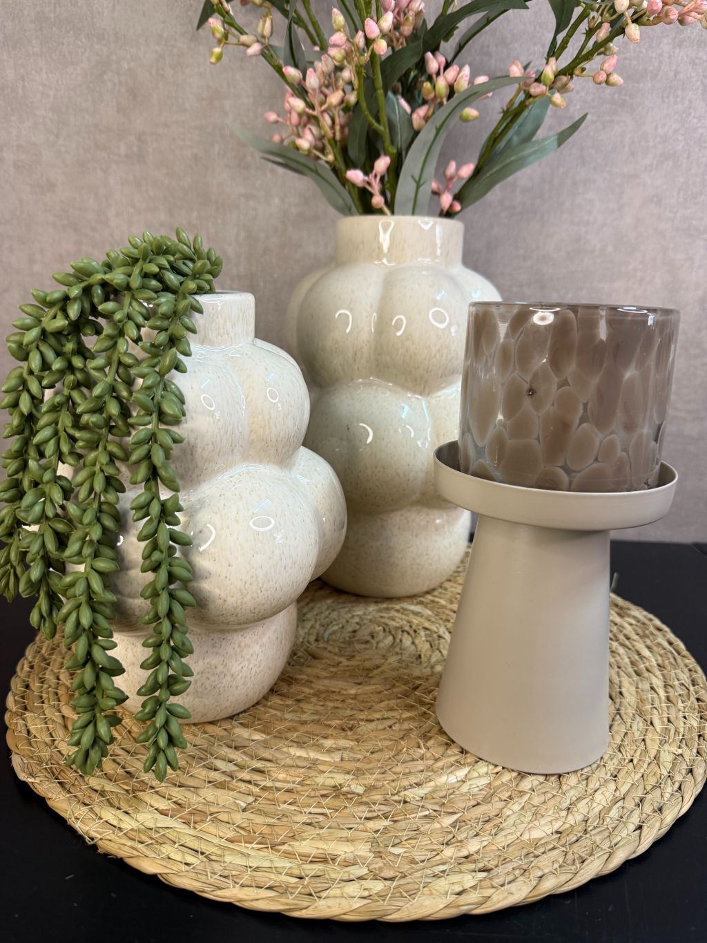 Tafel decoratie set Steffi met beige vazen, roze kunsttak, groene hangplant en waxinelichthouder op een ronde placemat.