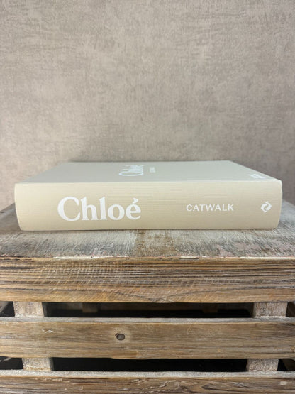 Beige hardcover tafelboek ‘Chloé Catwalk – The Complete 69’ op houten ondergrond, decoratief en stijlvol voor interieur of fashioncollectie.