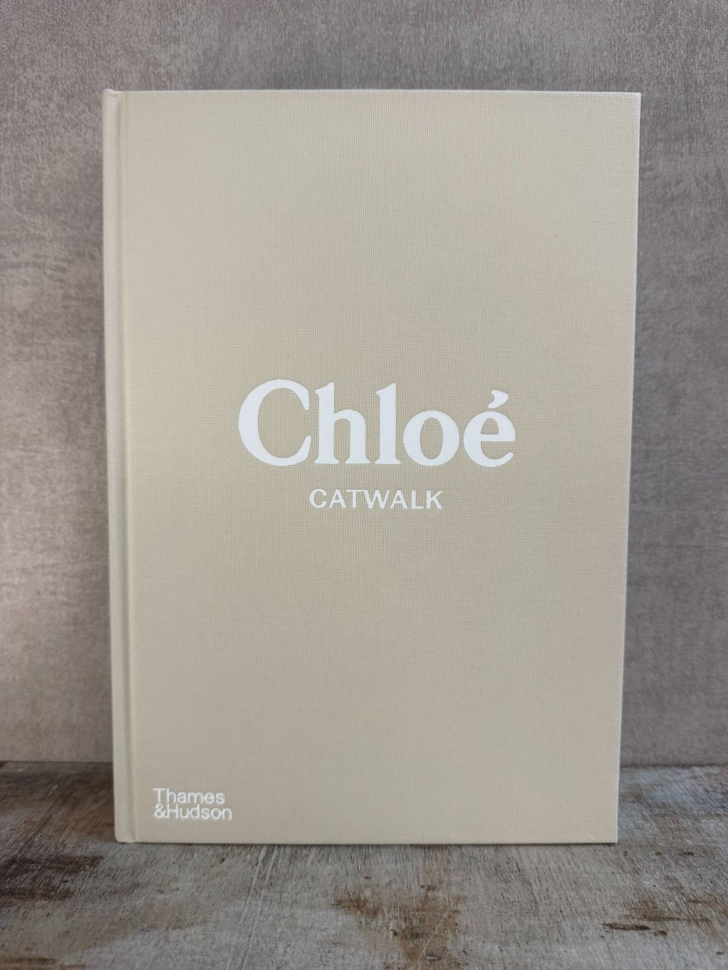 Beige hardcover tafelboek ‘Chloé Catwalk rechtop staand op een houten plank.
