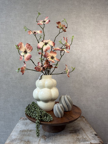 Tafel decoratie set Livara met houten dienblad, beige vaas, kleurrijke kunstbloemen, groene hangplant en decoratieve kaarsen.