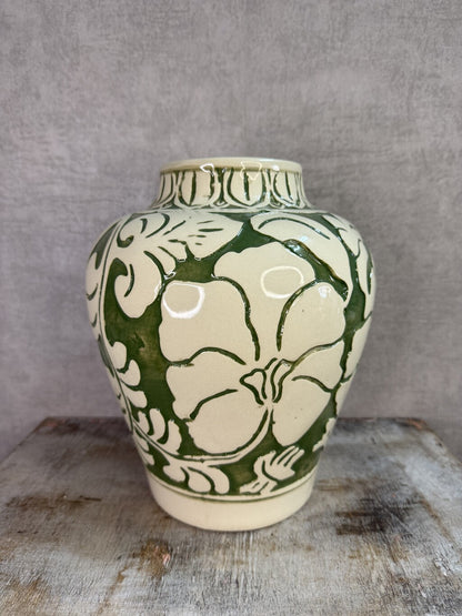 Beige keramieken vaas met groen bloemmotief van Mica op een houten ondergrond.