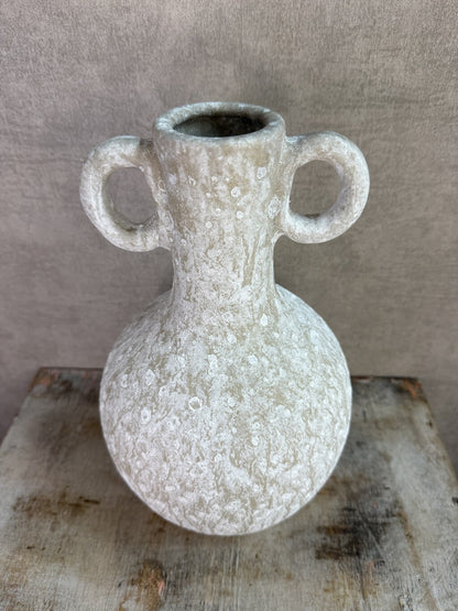 Beige keramieken kruikvaas met ronde vorm en twee decoratieve oren op een houten ondergrond.