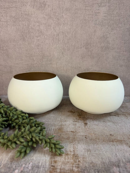 Twee waxinelichthouders Rapallo van Light & Living in crème met goud, bolvormig model op een houten ondergrond.