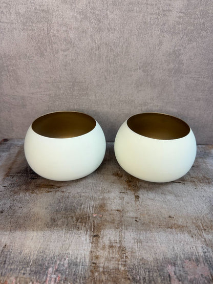 Twee waxinelichthouders Rapallo van Light & Living in crème met goud, bolvormig model op een houten ondergrond.