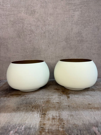 Twee waxinelichthouders Rapallo van Light & Living in crème met goud, bolvormig model op een houten ondergrond.