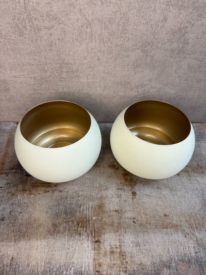 Twee waxinelichthouders Rapallo van Light & Living in crème met goud, bolvormig model op een houten ondergrond.