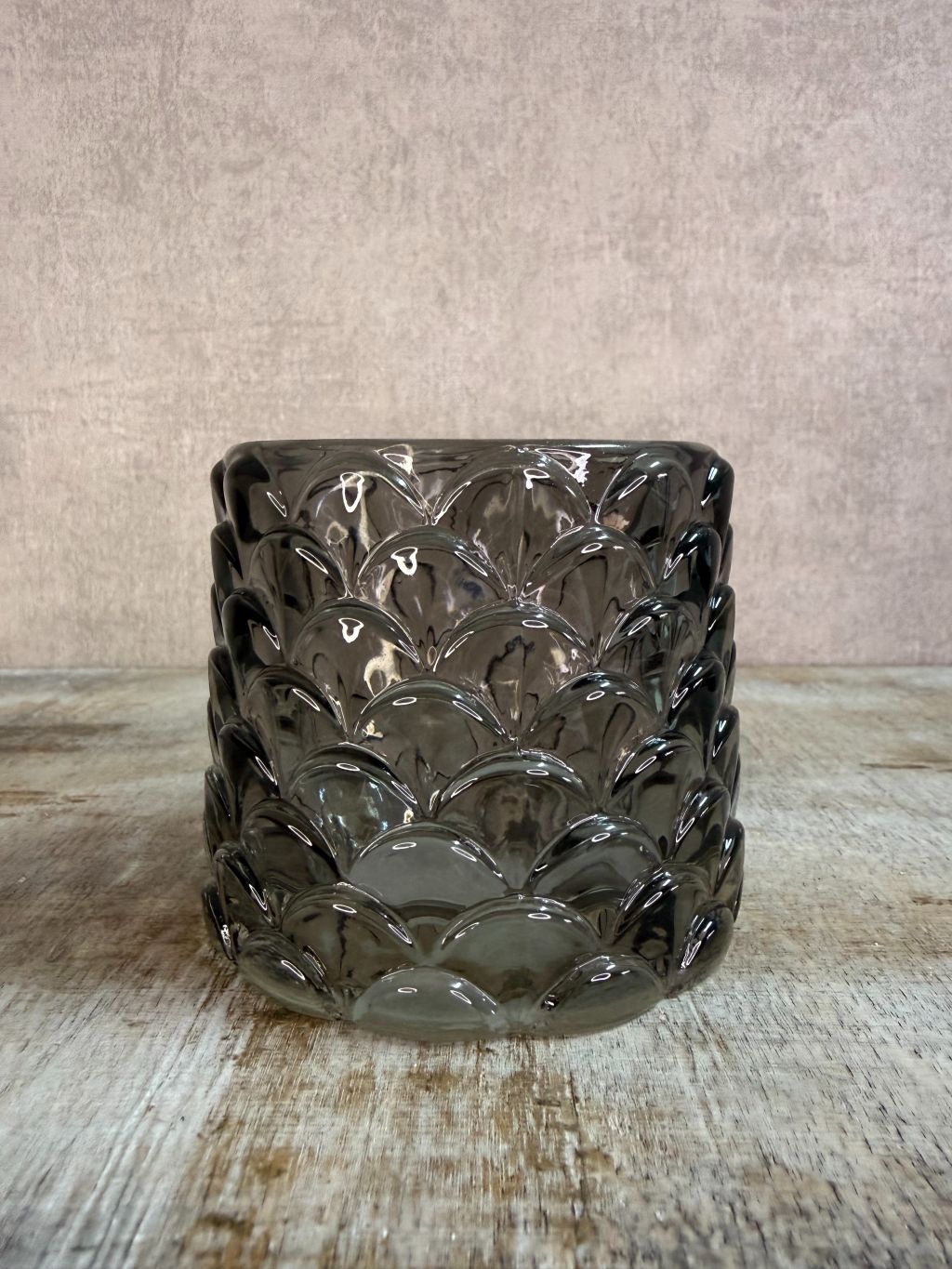 Transparant zwarte glazen waxinelichthouder Sculp met reliëfpatroon, geplaatst op een houten ondergrond.