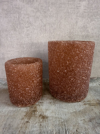 Bruine glazen waxinelichthouders met grove structuur in twee formaten op een houten ondergrond.