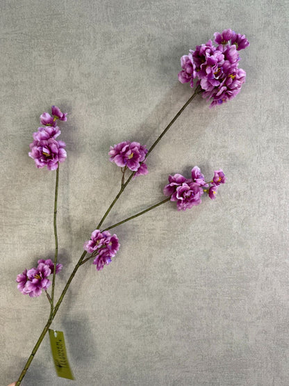 Zijden bloesemtak Prunus met paarse bloesems, slanke vertakking en een natuurlijke uitstraling tegen een neutrale achtergrond.